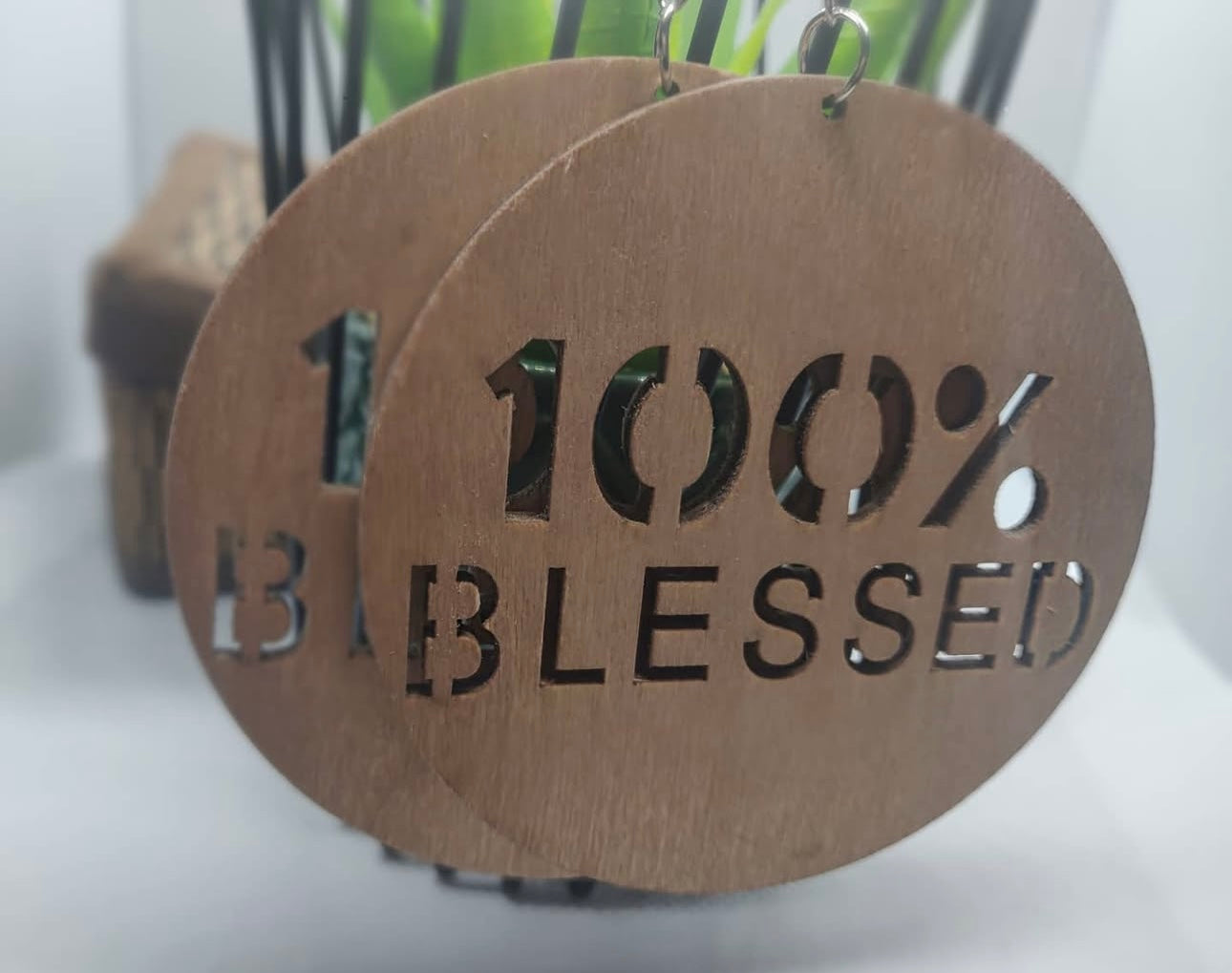 Wooden earrings with '100% Blessed' text on a white surface.