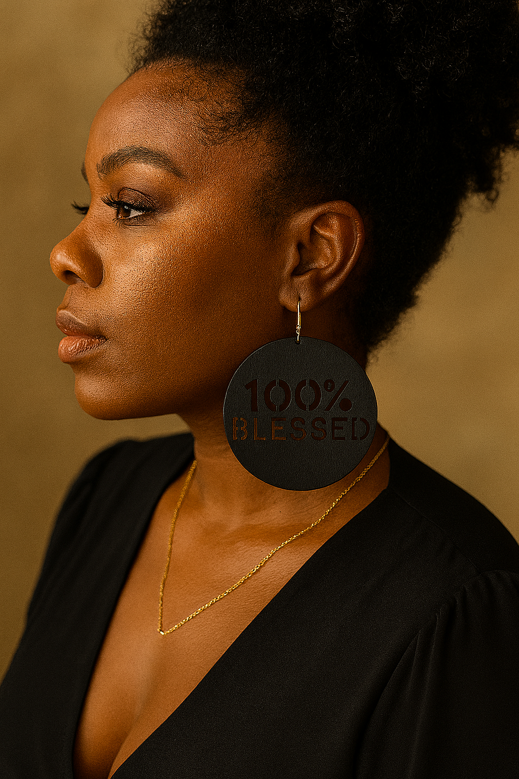 Woman wearing a black earring with '100% Blessed' text against a beige background