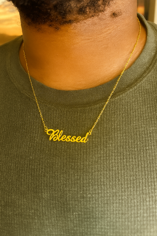 Gold necklace with 'Blessed' pendant on a person wearing a green shirt.